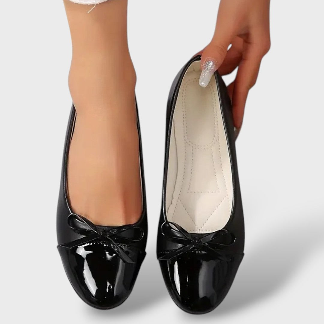 Women's black patent ballet flats with bow detail, flat sole, interior view