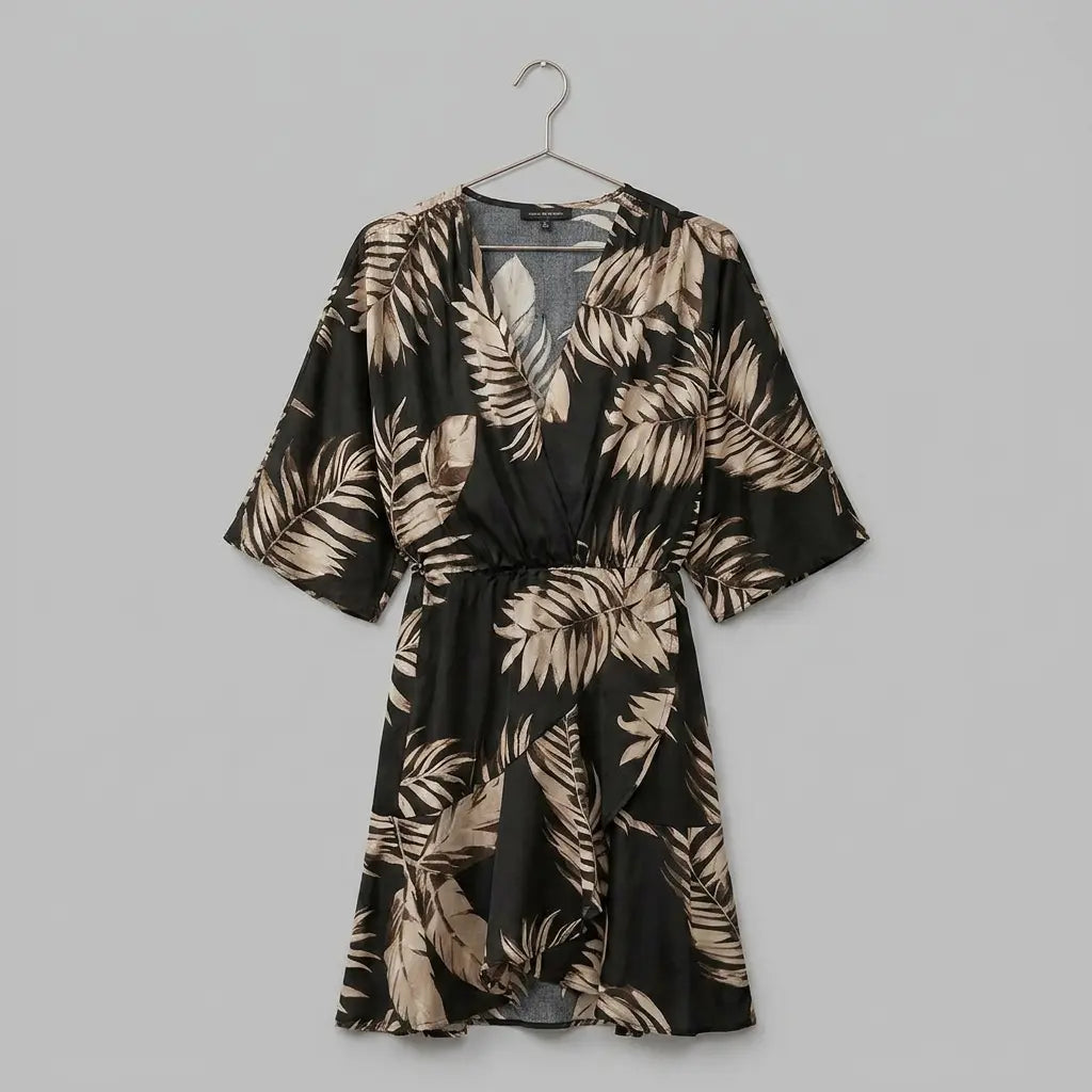 Mini wrap dress with batwing sleeves in black and gold palm leaf print on hanger