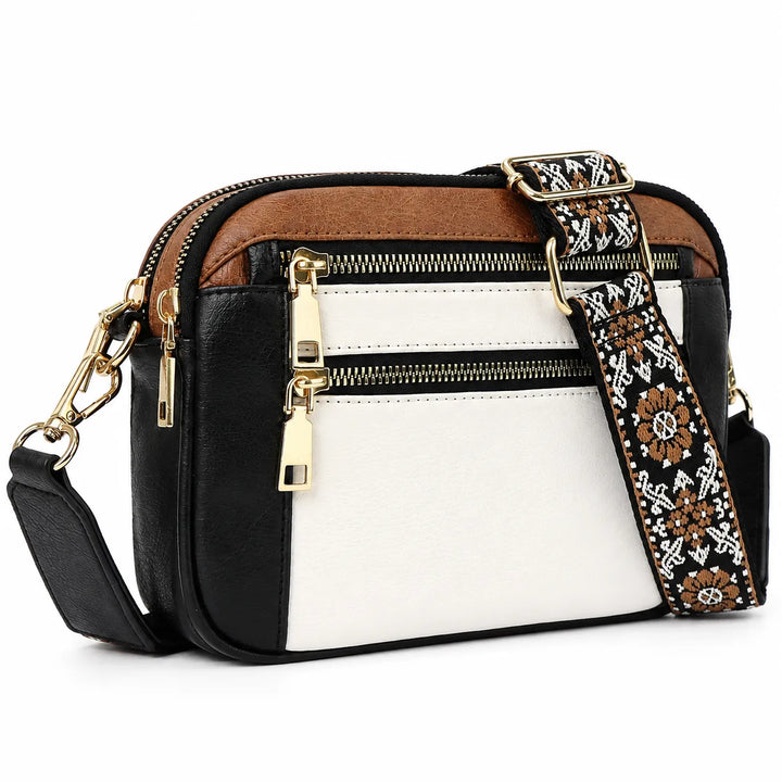 Close-up of crossbody camera bag showing front zip pocket and gold-tone hardware detail