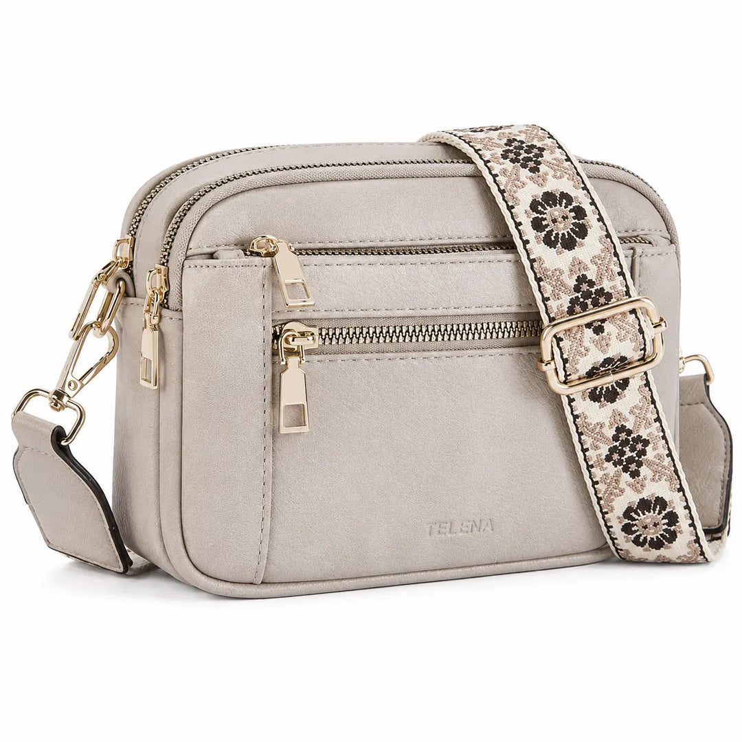 Detail view of crossbody camera bag showing zipper closure and two-tone leather trim