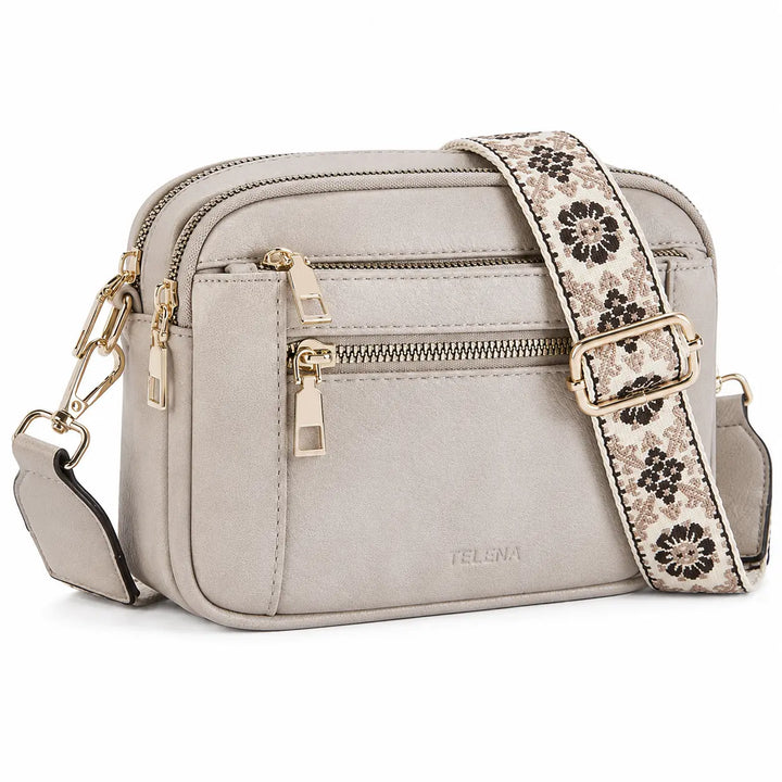 Detail view of crossbody camera bag showing zipper closure and two-tone leather trim