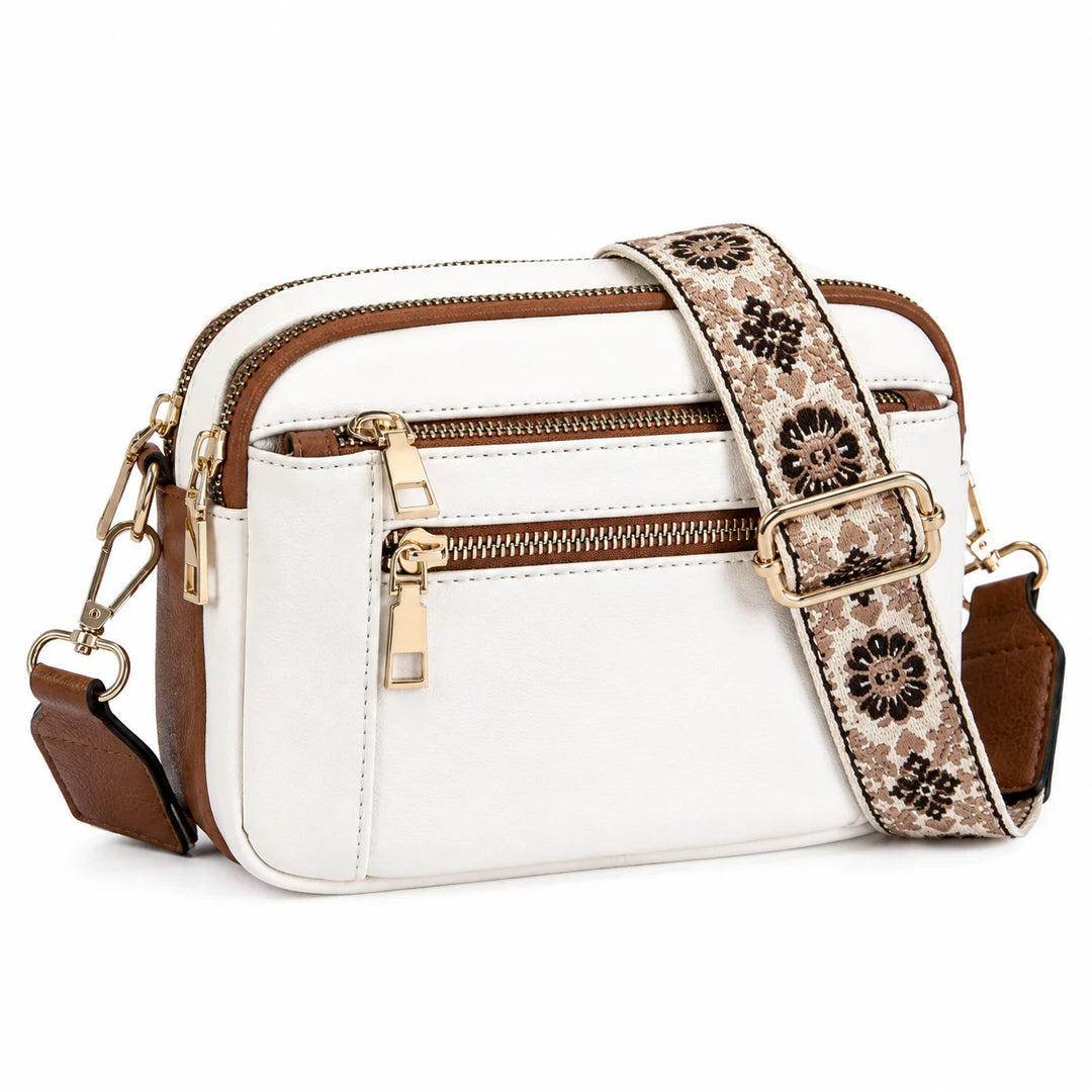 Structured camera crossbody bag in white with camel brown trim and gold hardware, flat lay