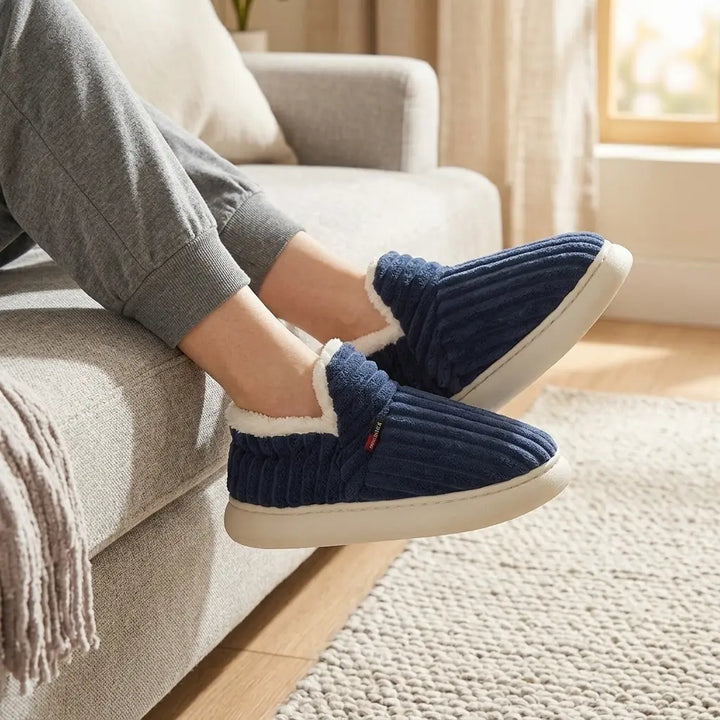 Ribbed corduroy house slippers in navy blue with cream sherpa lining, model seated