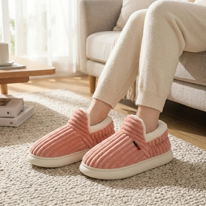 Ribbed corduroy house slippers in dusty rose with cream sherpa lining, front view on rug