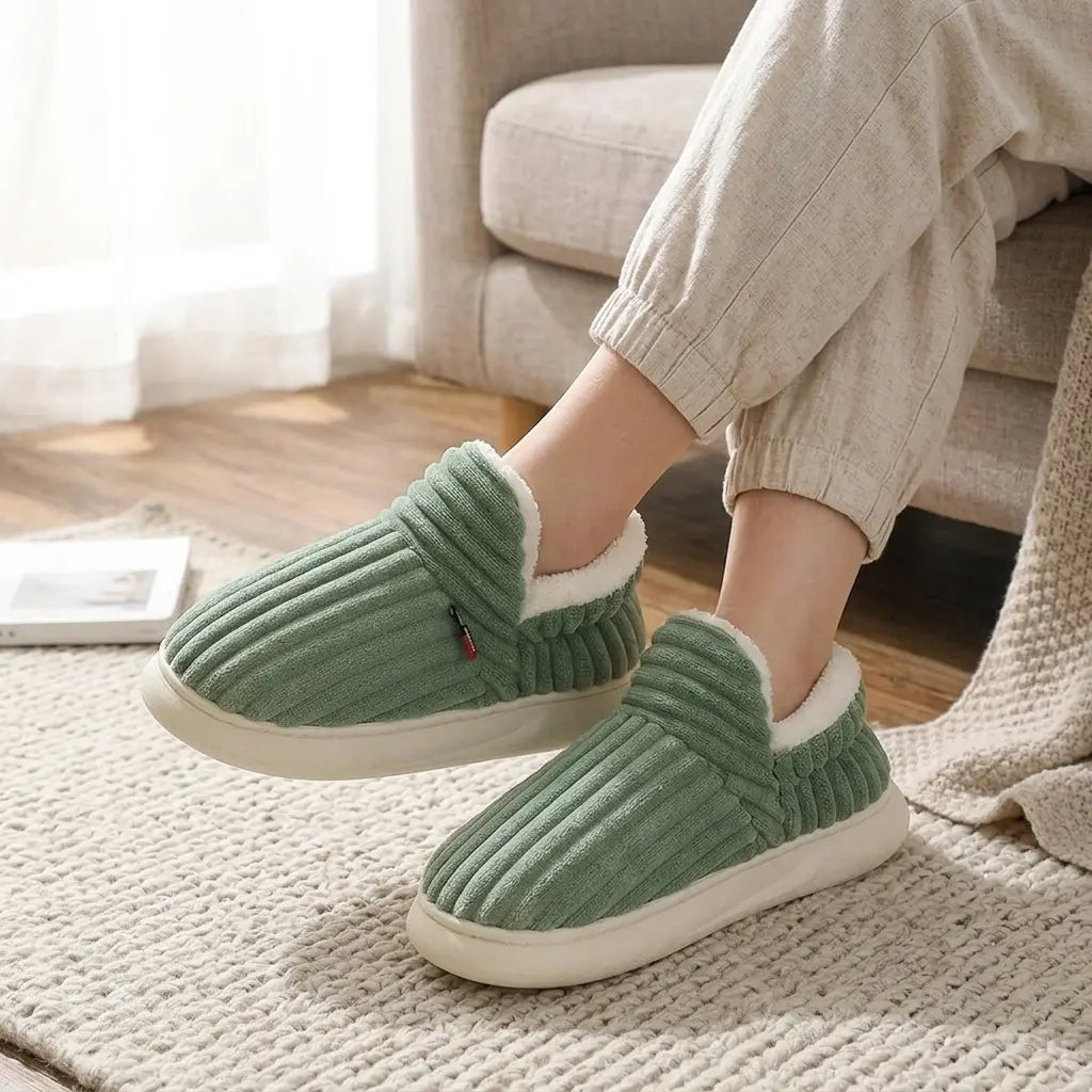 Ribbed corduroy house slippers in sage green with cream sherpa lining, side view on rug
