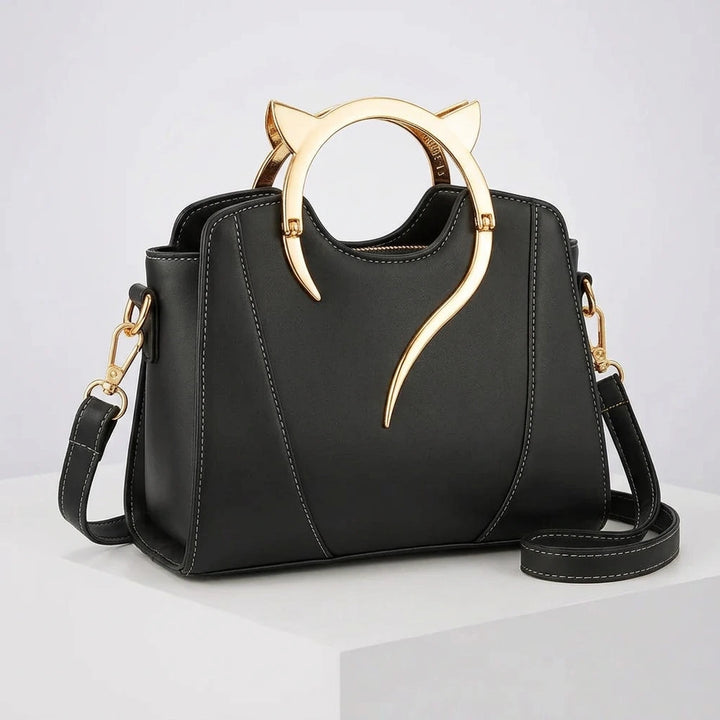 Front view of women's handbag with cat handle — gold cat-ear ring, structured black PU exterior and dual carry options