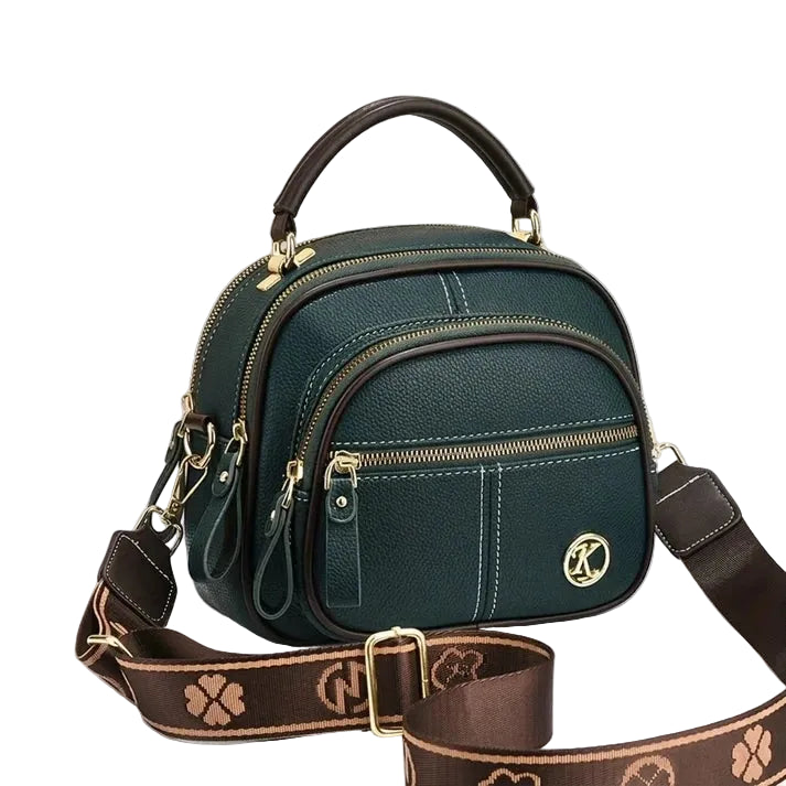 Green compact crossbody bag with brown shoulder strap on gray background