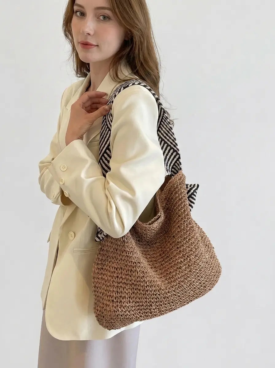 Model wearing woven shoulder bag in warm brown over shoulder, side view