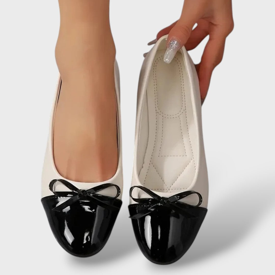 Women's beige ballet flats with black patent toe cap and bow, flat sole